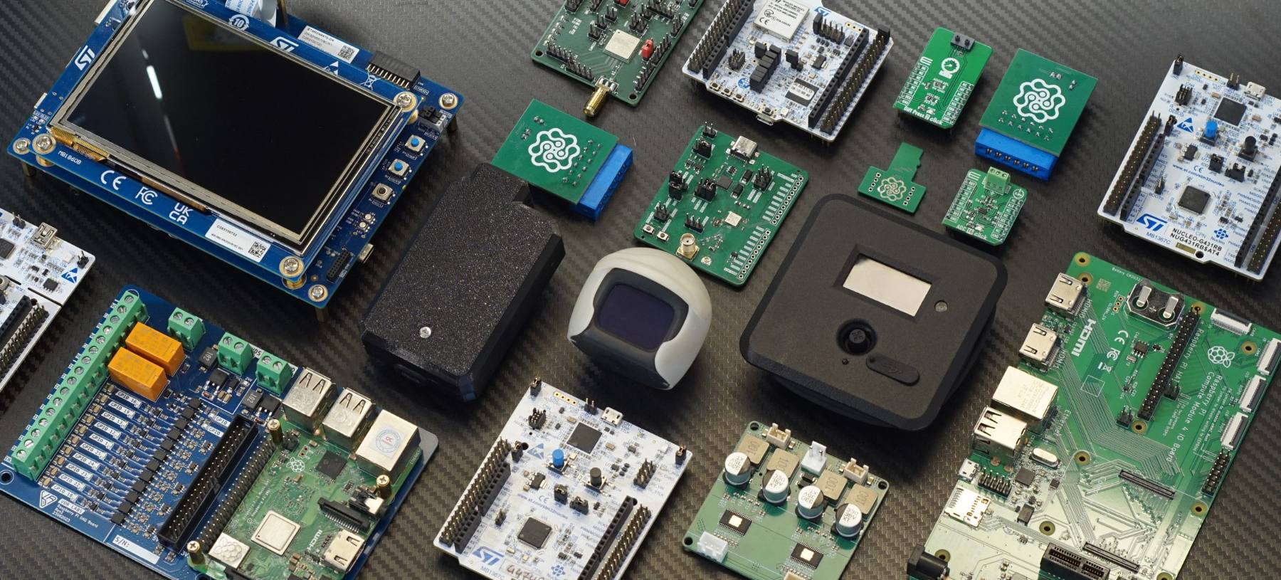 Evaluation boards, sensor modules and enclosures laid out on a carbon-weave bench